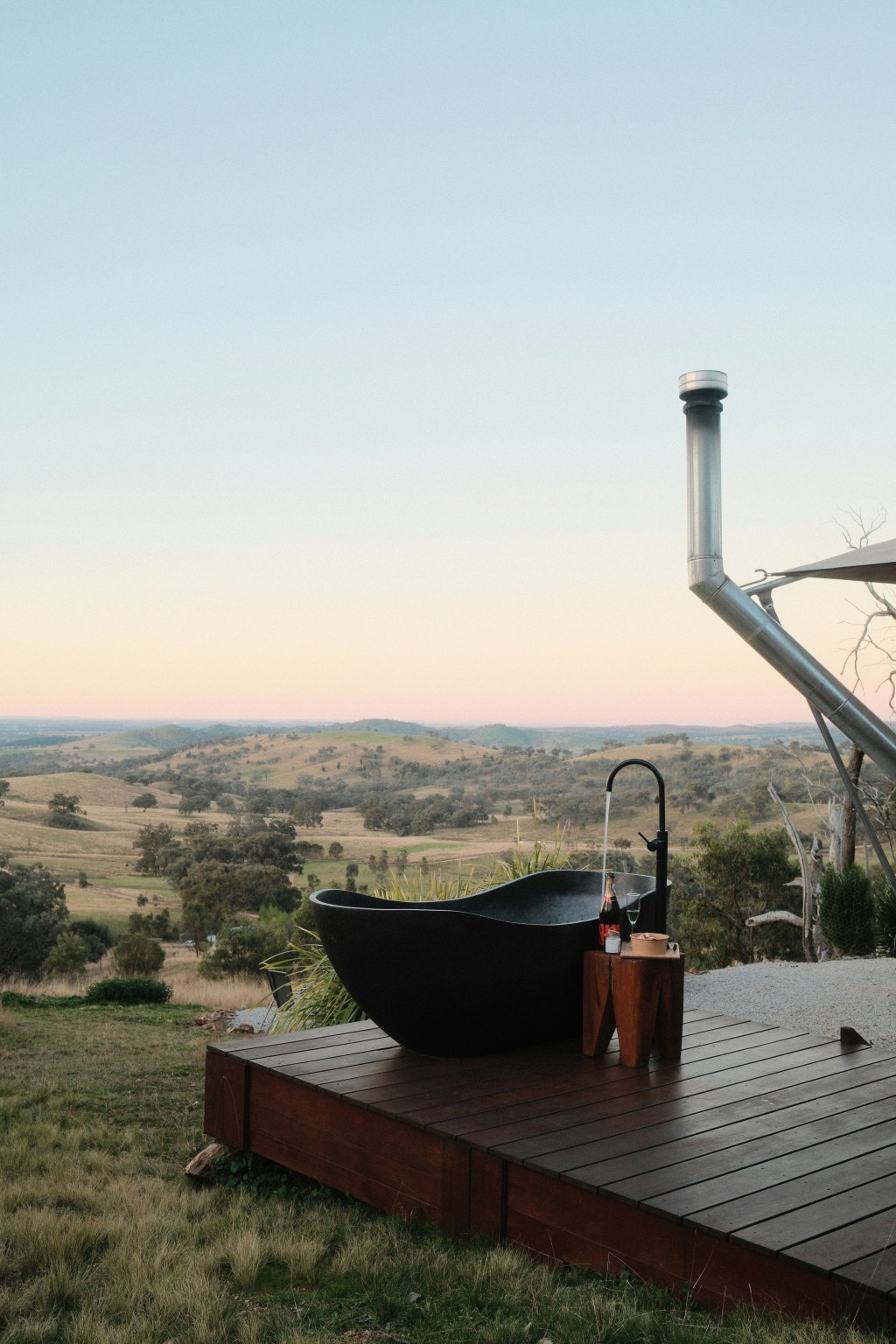 A view of an outdoor bath overlooking a valley as the sun sets,. The bath is empty