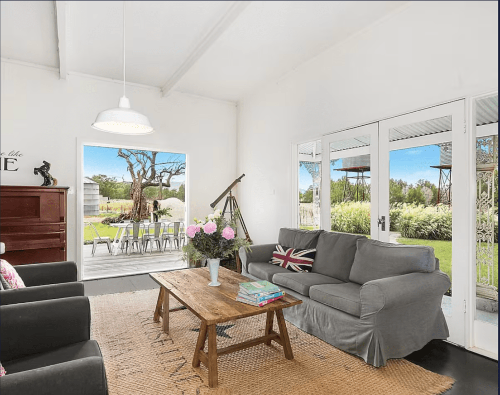 Image of living room in Trelawney Farm, Bombira Mudgee. Lounges open onto vistas of surrounding farm. Windmills visible. 